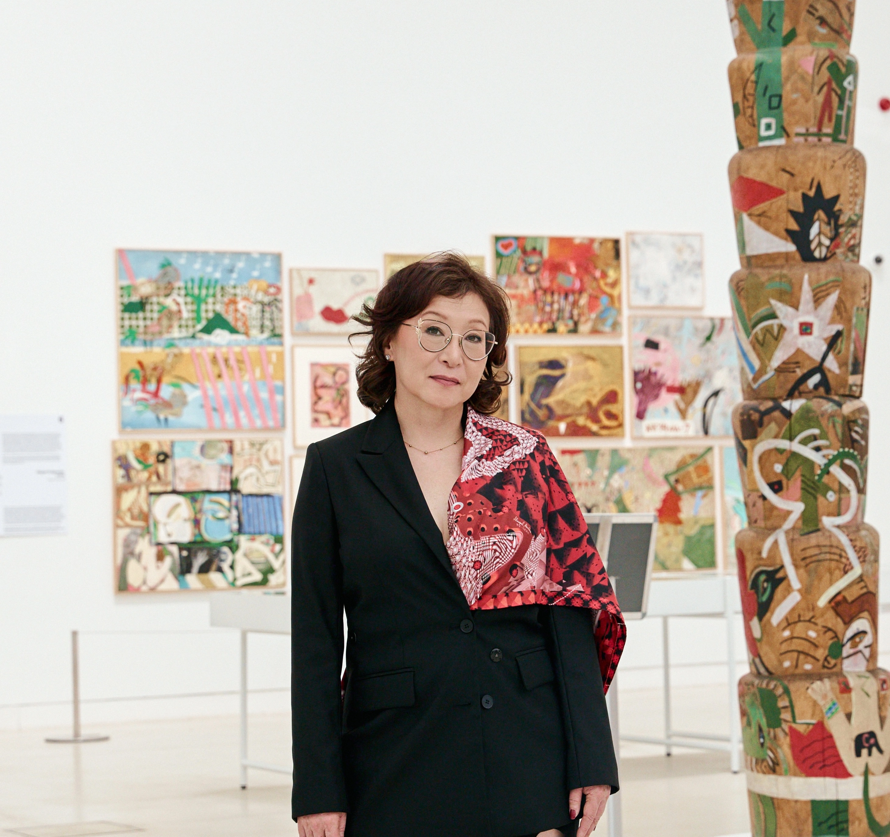 Artist Almagul Menlibayeva standing in front of her artworks